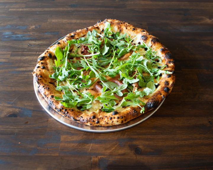 Prosciutto pizza with garlic cream sauce, fresh mozzarella, arugula and shaved Parmesan