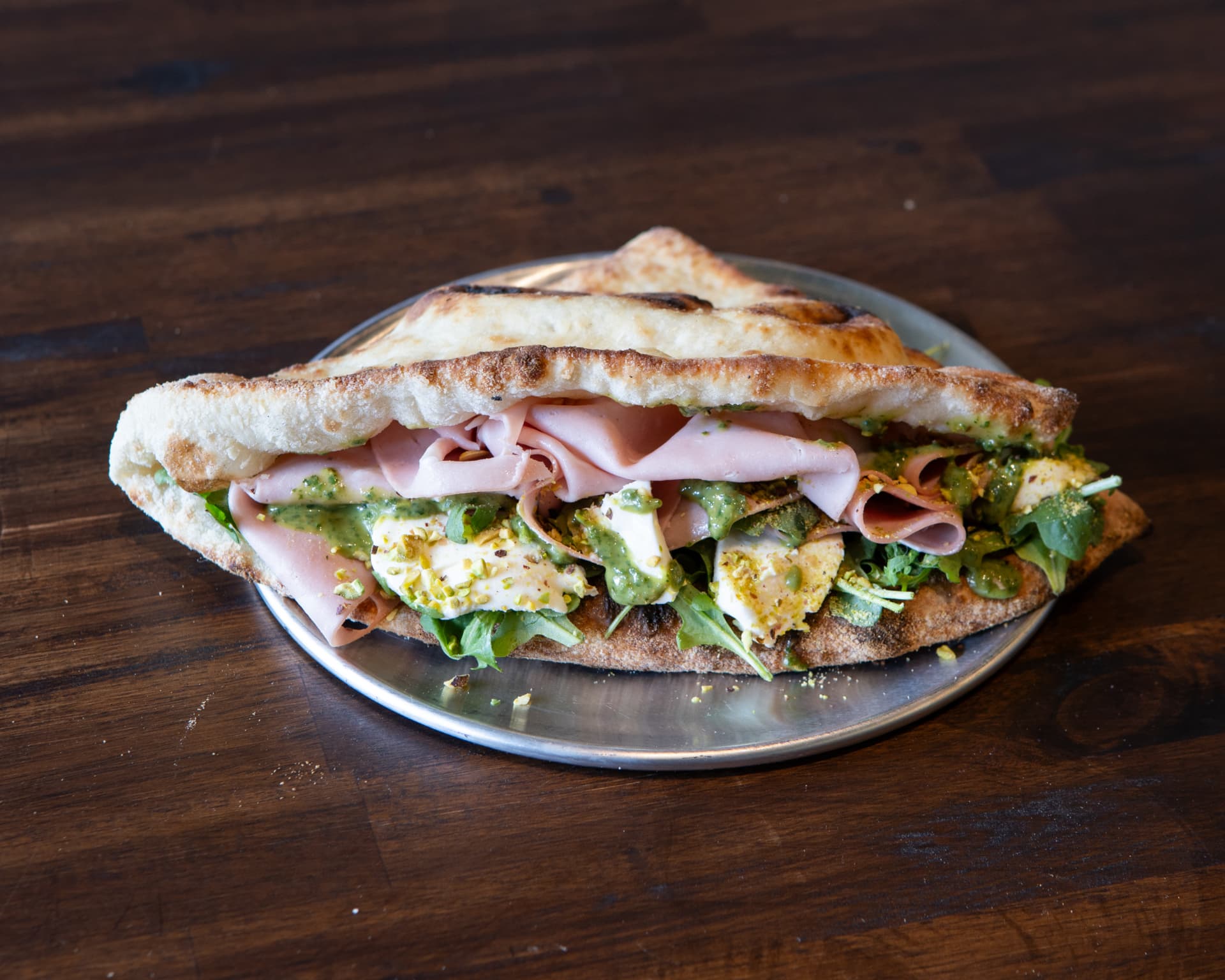 Mortadella and ricotta panuozzo with pistachio pesto and arugula