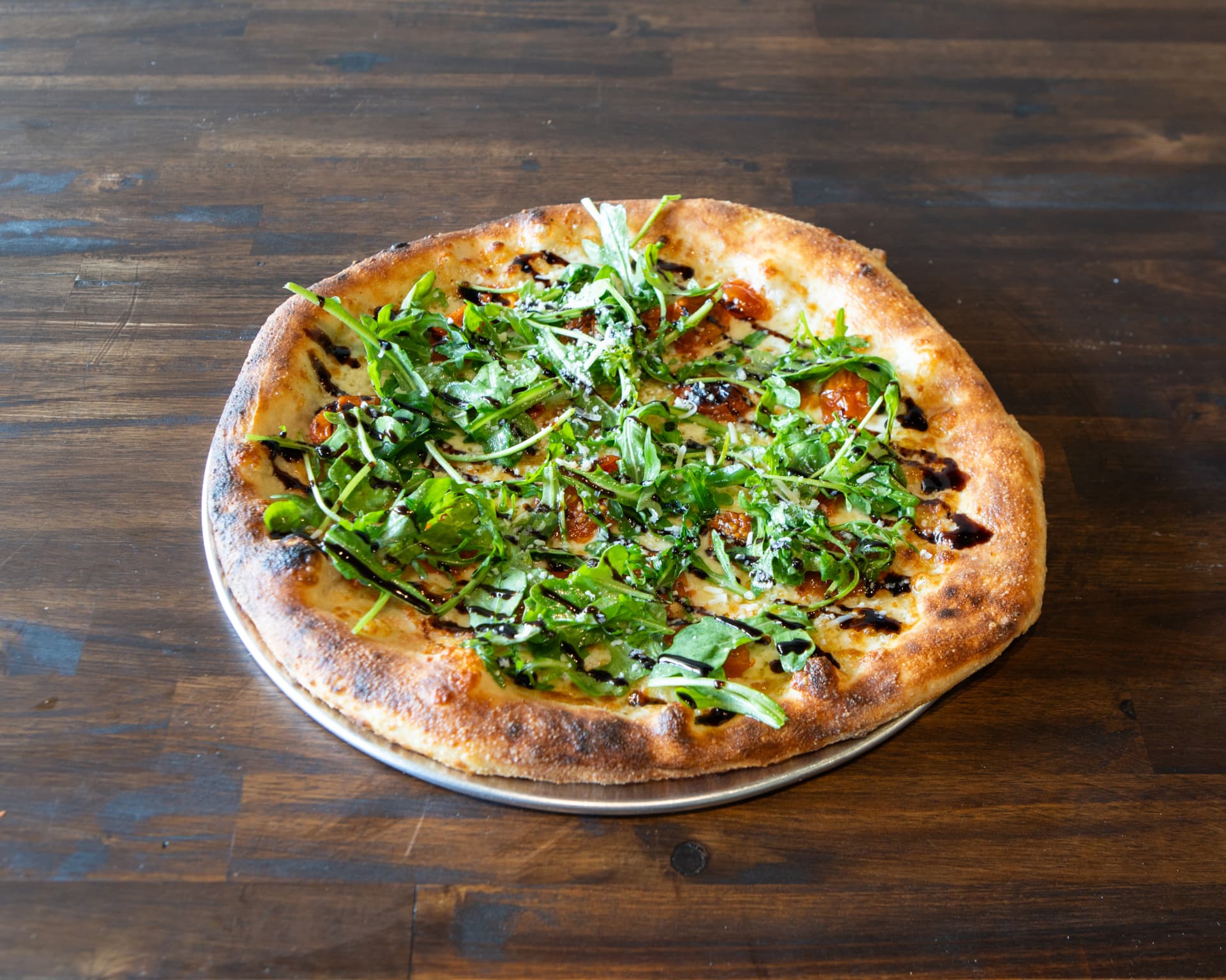 Nonna pizza with fresh mozzarella, roasted cherry tomatoes, arugula and balsamic glaze
