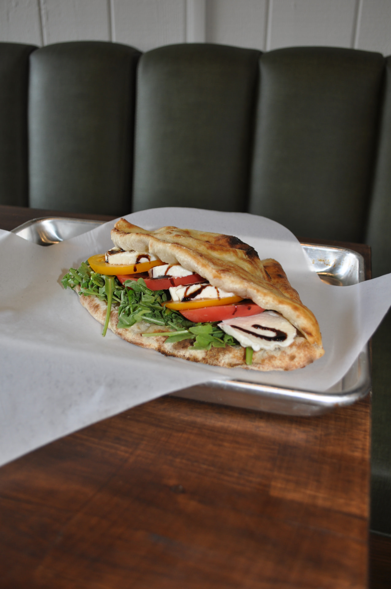 Caprese panuozzo with fresh mozzarella, tomatoes, greens and balsamic glaze